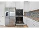 Kitchen with stainless steel appliances including refrigerator and double oven, white cabinets and granite counters at 17618 Cortes Creek Blvd, Spring Hill, FL 34610
