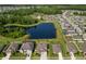 Picturesque aerial view of a community with a scenic pond surrounded by green trees and well-spaced houses at 18428 Malinche Loop, Spring Hill, FL 34610
