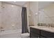 Well-lit bathroom includes a shower-tub combo with tiled walls, granite counter and dark cabinetry at 18428 Malinche Loop, Spring Hill, FL 34610