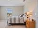 Neutral bedroom showcases a queen bed with striped linens, a nightstand, and a window at 18428 Malinche Loop, Spring Hill, FL 34610