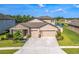 Beautiful home featuring a manicured lawn, stone accents, a three-car garage and a picturesque lake view at 18428 Malinche Loop, Spring Hill, FL 34610