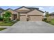 Inviting front exterior of a home with a three-car garage, stone accents, and a well-manicured lawn at 18428 Malinche Loop, Spring Hill, FL 34610