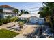 Aerial view of a cute home with white exterior, a metal roof, lovely tropical landscaping, and a large driveway at 1857 Bayou Grande Ne Blvd, St Petersburg, FL 33703