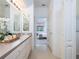 Long bathroom with double mirrors, sink, and view to bedroom at 19137 Lake Audubon Dr, Tampa, FL 33647