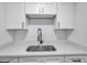 Close-up of a kitchen sink with modern faucet, white countertops, and subway tile backsplash at 2353 Shelley St # 6, Clearwater, FL 33765