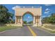 Grand entrance to the community featuring a monument, lush landscaping, and a scenic street at 2447 Ecuadorian Way # 11, Clearwater, FL 33763