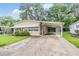Exterior of home featuring a carport, awnings, and landscaped front yard at 3542 Castle Dr, Zephyrhills, FL 33540