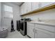 Well-lit laundry room with modern appliances, tile flooring, overhead cabinets, and sink at 3952 Aldea Way, Wesley Chapel, FL 33543