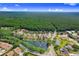 From above, a residence is surrounded by a canopy of trees, offering private serene living near a peaceful pond at 4012 Wellington Pkwy, Palm Harbor, FL 34685