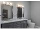 Bathroom with a double vanity, marble countertop, gray cabinets, dual sinks and framed mirrors with overhead lighting at 4012 Wellington Pkwy, Palm Harbor, FL 34685