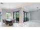 Open dining room with modern light fixture, floor to ceiling sliding glass doors leading to outdoor living at 4012 Wellington Pkwy, Palm Harbor, FL 34685