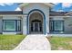 Welcoming front entrance featuring an arched doorway, complemented by landscaped surroundings and gray roofing at 4012 Wellington Pkwy, Palm Harbor, FL 34685