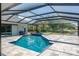 Screened-in pool with a travertine deck and lake view at 4012 Wellington Pkwy, Palm Harbor, FL 34685