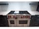 Close up view of a stainless steel dual oven stove with red knobs and custom cabinetry at 4012 Wellington Pkwy, Palm Harbor, FL 34685