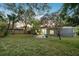View of the backyard features green grass, mature shade trees, and a cozy patio area with colorful seating at 4324 S Clark Ave, Tampa, FL 33611