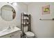Well-lit bathroom featuring a clean vanity, modern fixtures, decorative mirror, and a shelving unit at 4324 S Clark Ave, Tampa, FL 33611