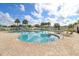 A stunning community pool with a brick deck is surrounded by seating and palm trees under a sunny sky at 4921 Wessex Way, Land O Lakes, FL 34639