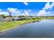 A waterfront home is set against a beautiful blue sky, with lush green lawn leading to the lake at 4921 Wessex Way, Land O Lakes, FL 34639
