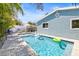Backyard pool with lounge chairs, white picket fence, and inflatable unicorn in a fenced-in yard with blue siding at 501 Janice Pl, Indian Rocks Beach, FL 33785