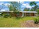 Inviting single-story home with a classic brick facade, mature trees, and a lush green lawn at 6104 Palm Ave, Gibsonton, FL 33534