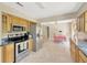 Open kitchen with tile floors, stainless appliances, wood cabinets, and adjacent dining space with checkered tablecloth at 6104 Palm Ave, Gibsonton, FL 33534