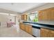 Bright eat-in kitchen with tile floors, light wood cabinets, granite countertops, and stainless steel dishwasher at 6104 Palm Ave, Gibsonton, FL 33534