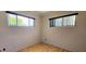 Bright bedroom featuring two windows, wood-look flooring, and neutral colored walls at 6825 Hammock Rd, Port Richey, FL 34668