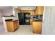 Charming kitchen featuring wood cabinets, black appliances, and granite countertops at 6825 Hammock Rd, Port Richey, FL 34668