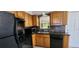 Kitchen featuring wood cabinets, black appliances, and stone countertops at 6825 Hammock Rd, Port Richey, FL 34668