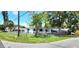 Street view of a well-maintained single-story home with a carport, a fenced yard, and mature trees at 6825 Hammock Rd, Port Richey, FL 34668