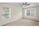 Comfortable bedroom with neutral walls and carpet featuring a ceiling fan and two windows at 7249 Bridgeview Dr, Wesley Chapel, FL 33545