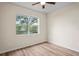 A sunny bedroom featuring hardwood floors, a ceiling fan, and a large window overlooking trees at 7249 Bridgeview Dr, Wesley Chapel, FL 33545