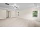 Spacious main bedroom with a tray ceiling and carpeted floors featuring a ceiling fan and two windows at 7249 Bridgeview Dr, Wesley Chapel, FL 33545