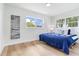 Bright bedroom with light hardwood floors, a blue bed, and two windows providing ample natural light at 7500 16Th N St, St Petersburg, FL 33702