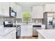 Well-lit kitchen features stainless steel appliances, white cabinets, quartz countertops, and stylish backsplash at 7500 16Th N St, St Petersburg, FL 33702