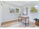 Bright home office space featuring hardwood floors, neutral paint, two windows, and modern desk with transparent chair at 7500 16Th N St, St Petersburg, FL 33702