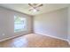 Bright bedroom features neutral paint, tile flooring, ceiling fan and a window with a green backyard view at 10219 Millport Dr, Tampa, FL 33626
