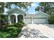 Charming home with a three-car garage and covered entryway, surrounded by lush landscaping and mature trees at 10219 Millport Dr, Tampa, FL 33626