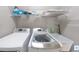 Bright laundry room with modern washer and dryer, sink and storage shelving at 10219 Millport Dr, Tampa, FL 33626