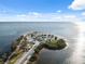 Scenic aerial view of a sandy beach, palm trees, and tropical waterway under sunny skies at 108 Shore Dr, Tarpon Springs, FL 34689