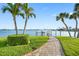 Well maintained backyard with stone paver walkway, lush green lawn, and water views at 11000 8Th E St, Treasure Island, FL 33706