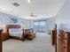 Spacious main bedroom with water view, plush carpet, ceiling fan, and stylish wooden furniture at 11000 8Th E St, Treasure Island, FL 33706