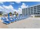 Picturesque beach view with blue lounge chairs, umbrellas, and building on the sand, perfect for seaside relaxation at 11500 Gulf Blvd # 513, Treasure Island, FL 33706