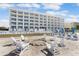 Beautiful beachfront condo building with private beach access and comfortable lounge chairs at 11500 Gulf Blvd # 513, Treasure Island, FL 33706