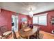 Elegant dining room with a chandelier, red accent wall, and hardwood floors at 11974 Rosetree S Pl, Seminole, FL 33772