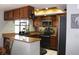 Well-lit kitchen with wooden cabinetry, granite countertops, and modern black appliances at 11974 Rosetree S Pl, Seminole, FL 33772