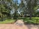 Landscaped backyard featuring mature trees and brick paver patio, perfect for outdoor entertaining at 12510 Sparkleberry Rd, Tampa, FL 33626