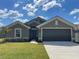 Charming single-story home with a well-manicured lawn, gray siding, and a two-car garage on a sunny day at 13187 Ogden Glade Rd, Dade City, FL 33525
