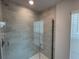 Modern shower with light gray subway tile, clear glass door, and chrome shower head at 13187 Ogden Glade Rd, Dade City, FL 33525