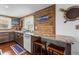 Charming kitchen featuring wood-paneled walls, a breakfast bar, and granite countertops at 14409 Birch St, Hudson, FL 34667